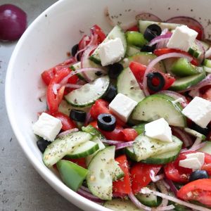 Greek cucumber salad in a white bowl.