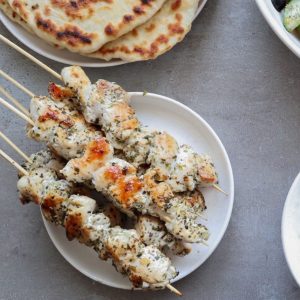 An overhead shot of chicken souvlaki on a white plate.
