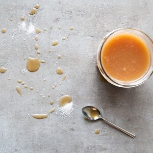 Caramel sauce with sea salt on a grey background.