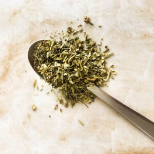 Italian seasoning on a spoon with a marble background.