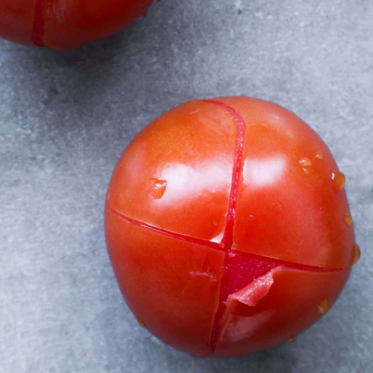 A cut tomato ready to be peeled.