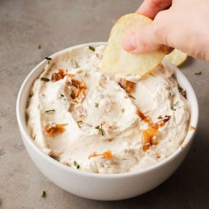 Caramelized onion dip with a hand and some crisps.
