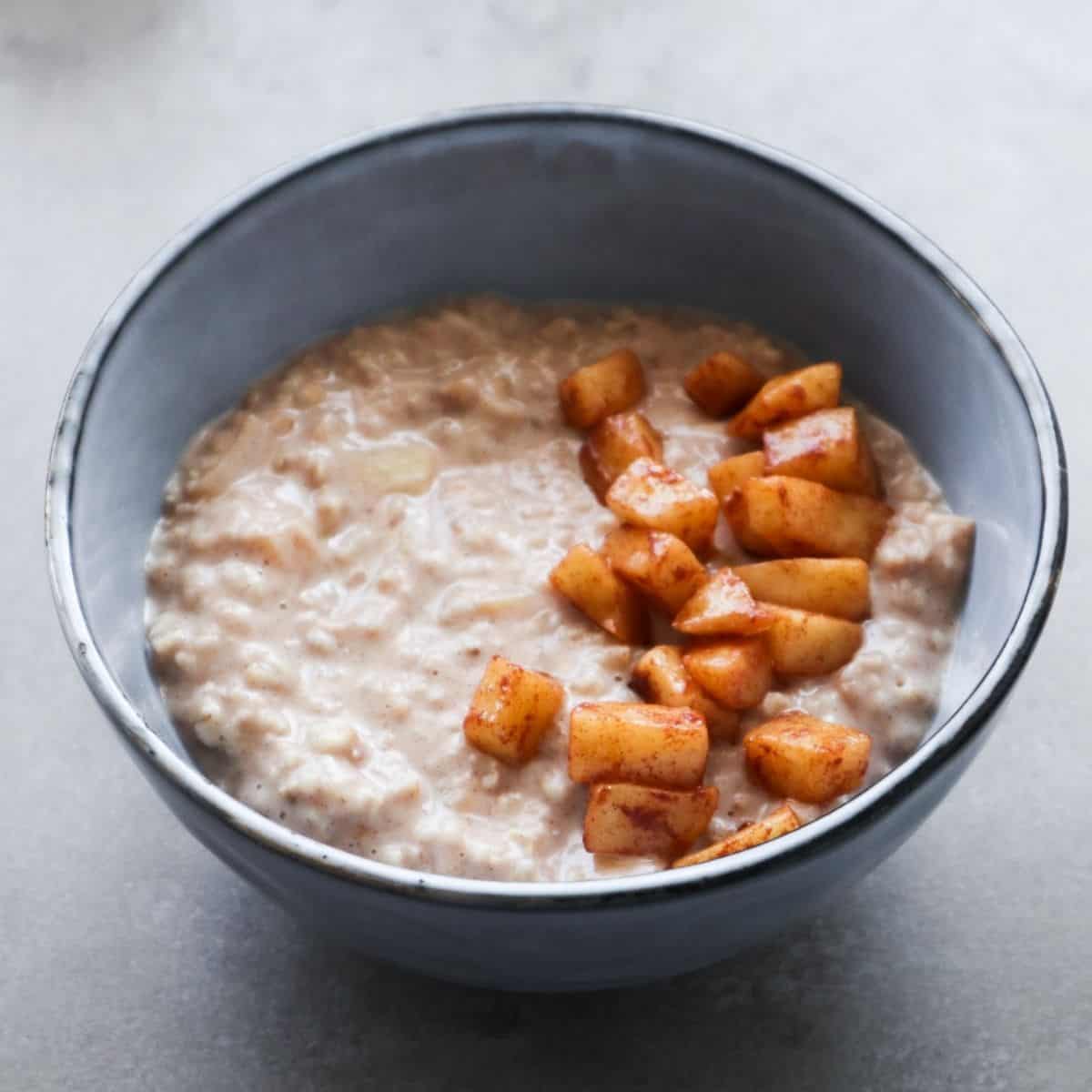 A close up of apple oatmeal with cinnamon in a blue bowl.