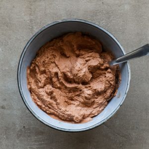 Heavy cream whipped up with cocoa powder and sugar in a blue bowl.