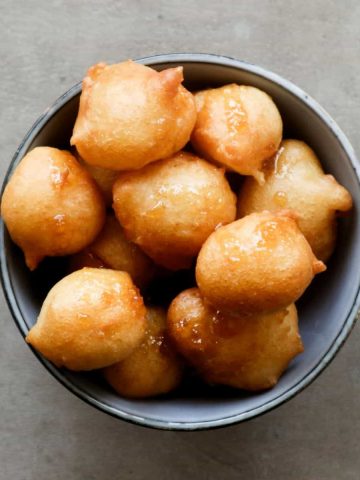 Overhead shot of loukoumade in a blue bowl.