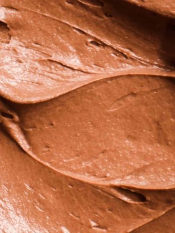 A close up of chocolate frosting with cocoa powder so you can see the texture.
