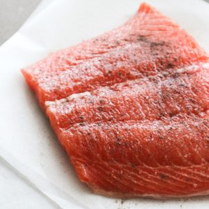 Fresh uncooked salmon on a sheet of baking paper for my pan seared salmon recipe.