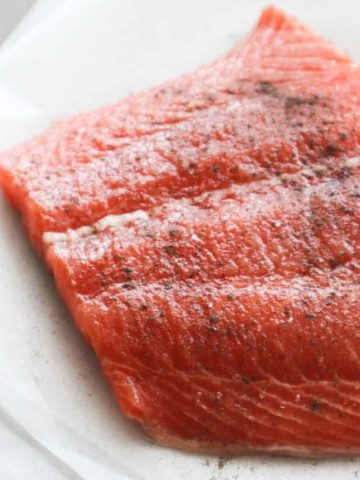 Fresh uncooked salmon on a sheet of baking paper for my pan seared salmon recipe.