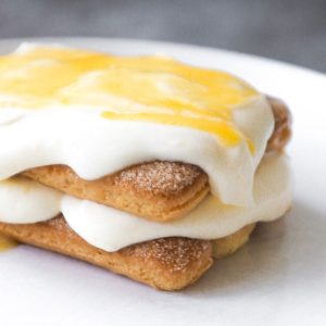 Individual lemon tiramisu with lemon curd on a white plate.