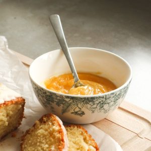 A close up of homemade dairy free lemon curd with a lemon loaf cake.