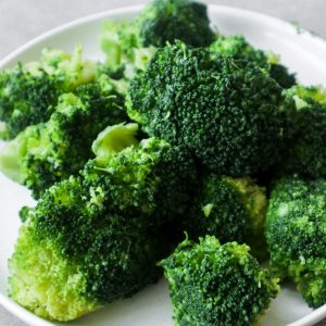 Cooked broccoli on a white plate.