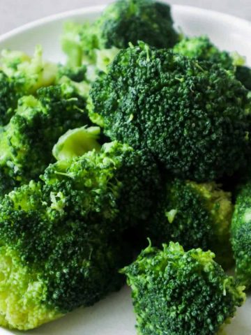 Cooked broccoli on a white plate.