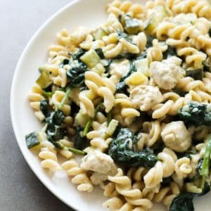 Boursin pasta with spinach and chicken on a white plate.