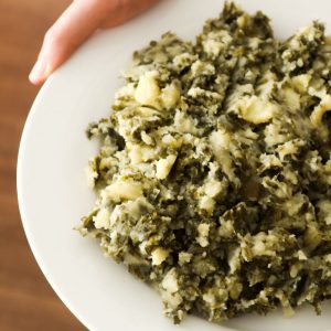 Mashed potatoes with kale on a white plate.