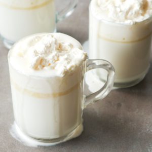 Hot white chocolate in glasses with whipped cream on top.