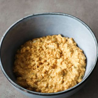 Egg salad with Greek yoghurt in a blue bowl on a Grey background.