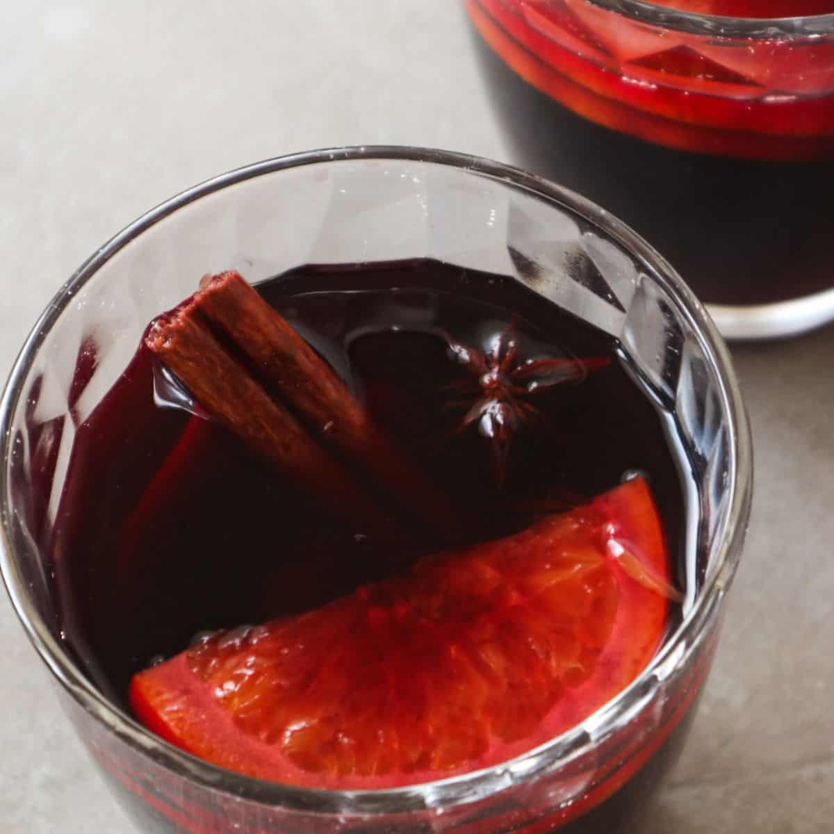 A glass mulled wine with orange slices, cinnamon stick and anis seed.