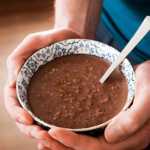 A close-up of a bowl with a healthy protein breakfast on a brown background.