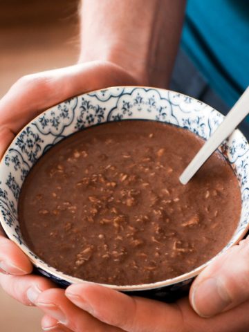 A close-up of a bowl with a healthy protein breakfast on a brown background.