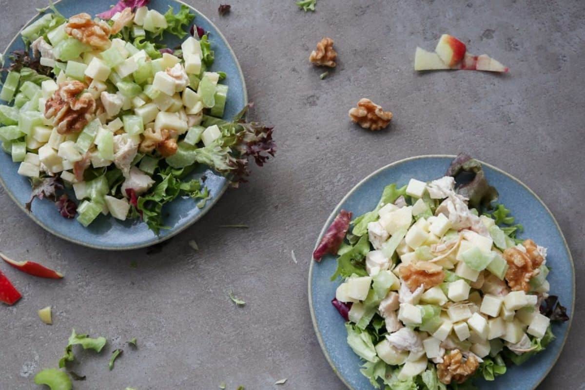 Waldof salad with chicken served on a blue plate with lettuce.