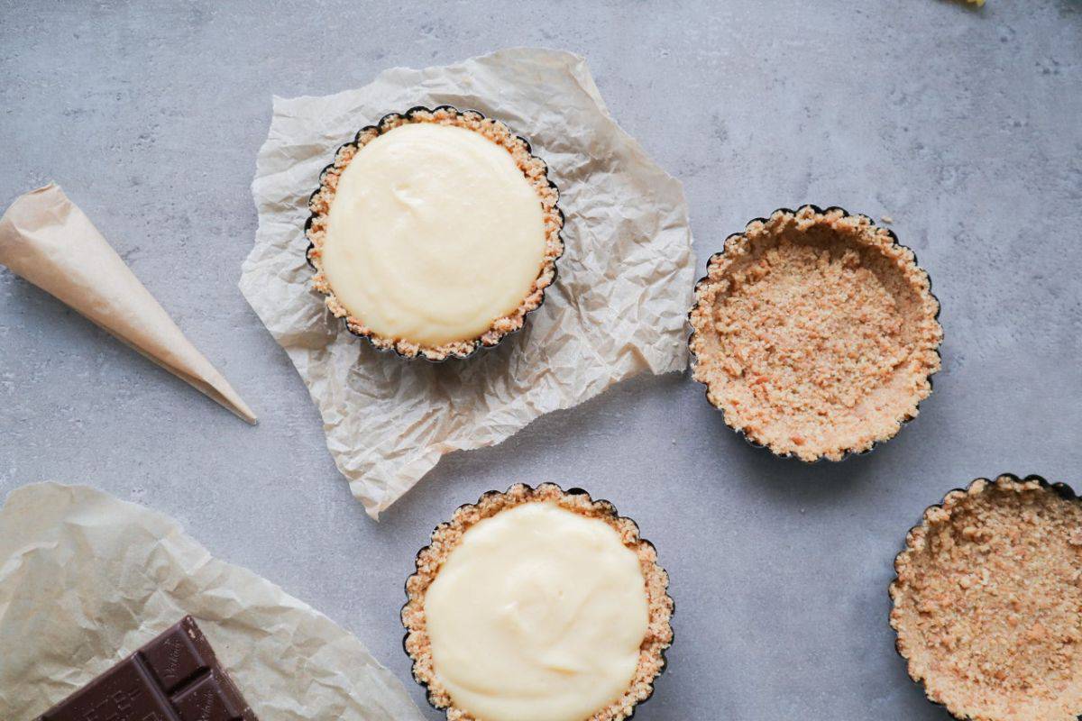 four little pie crusts while filling them with vanilla cream and decorating them with chocolate