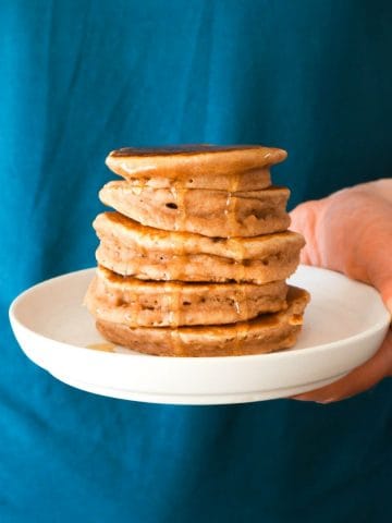 A stack of vanilla cinnamon pancakes on a blue background.