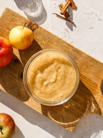 Homemade applesauce with three apples.