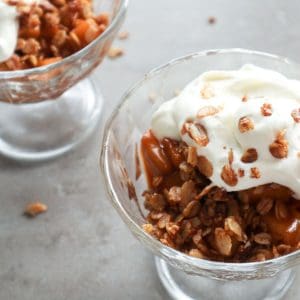 A bowl of stovetop apple crisp with heavy cream.