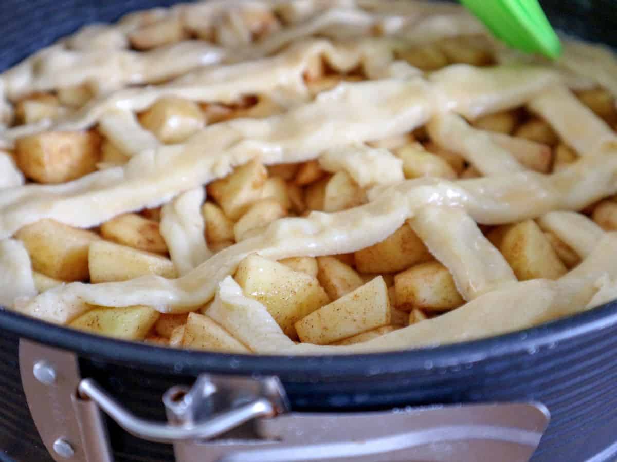 Uncooked appeltaart with egg wash and lace.