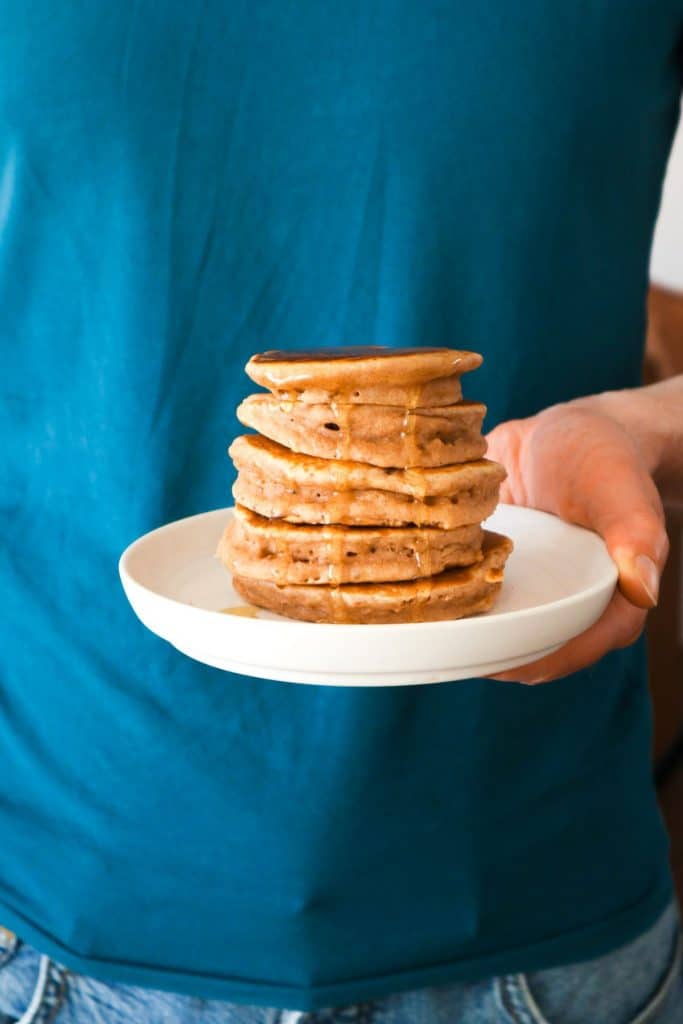 A hand holding a plate with cinnamon pancakes with vanilla and buttermilk.