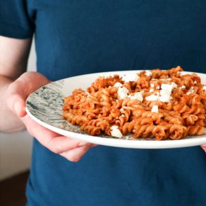 A close up of red pasta pesto on a plate.