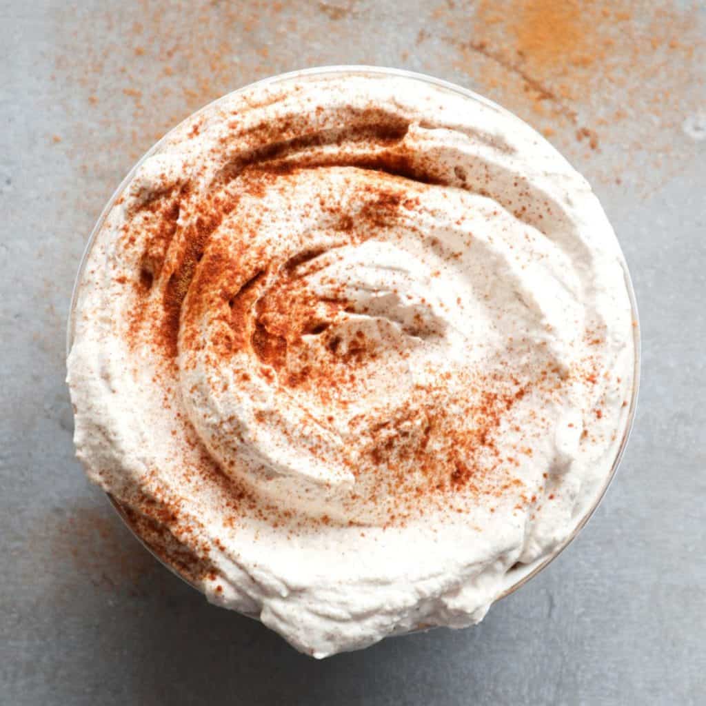 Whipped cream with cinnamon in a bowl with some extra cinnamon sprinkled on top.