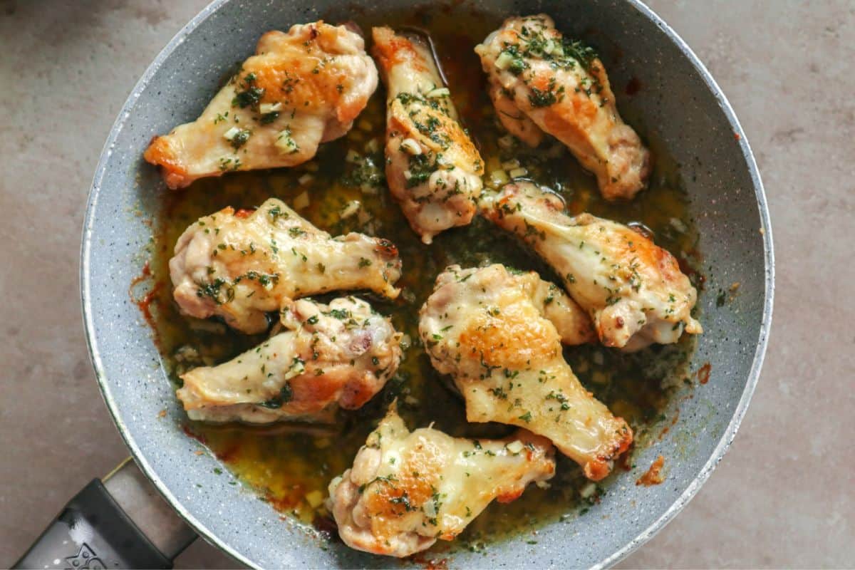 an overhead shot of garlic butter wings in a pan covered with parsley