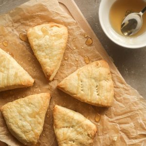 Scones on a wooden plank drizzled with honey.