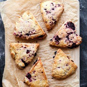 Six blackberry scones on a pieve of brown paper.