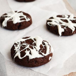 The featured image for this vegan Halloween cookie recipe with a close up of three spiderweb cookies.