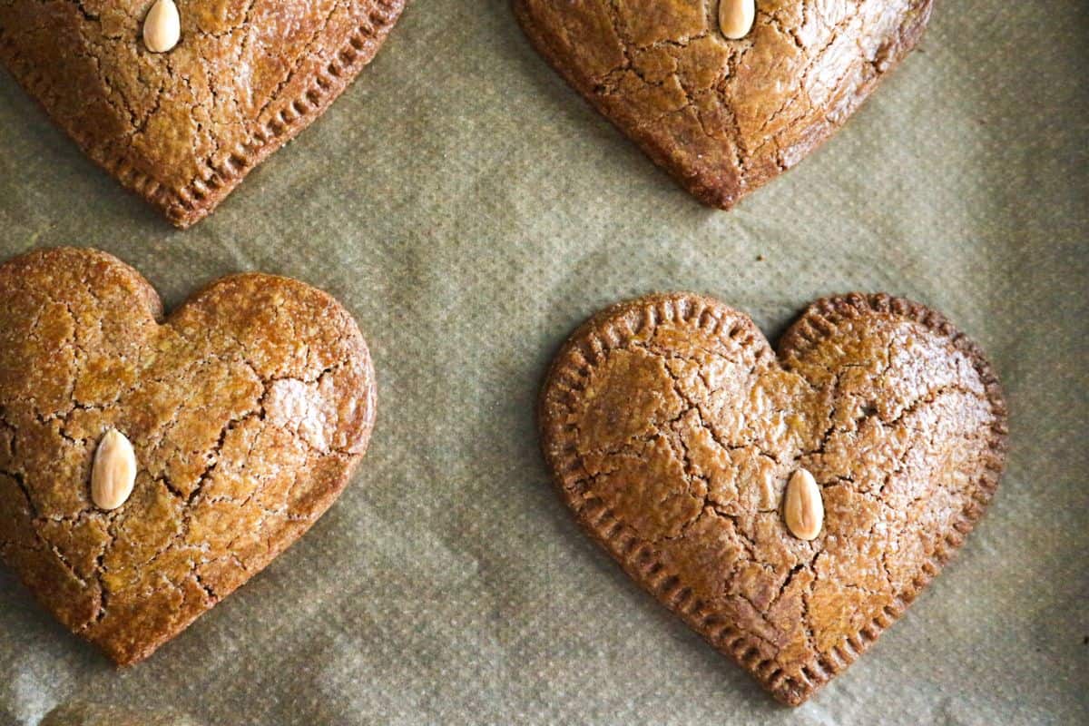 Four almond cookies on a baking tray.