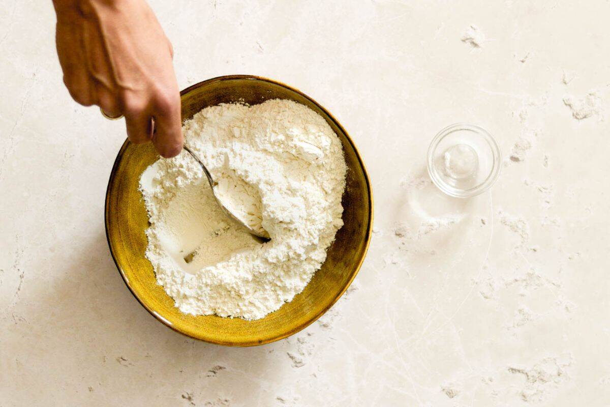 Mixing all-purpose flour with baking powder to make self-rising flour.