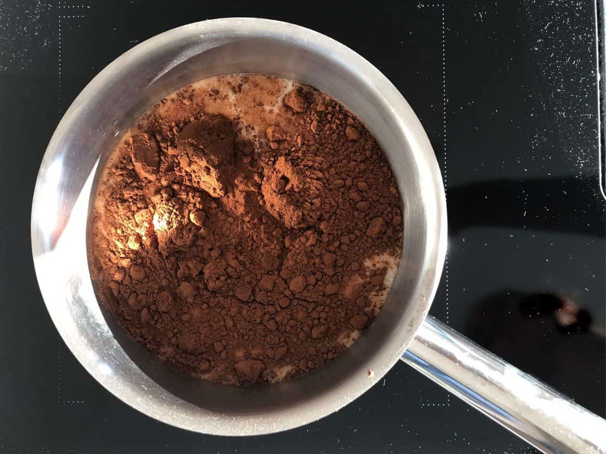 A saucepan with milk and cocoa powder.